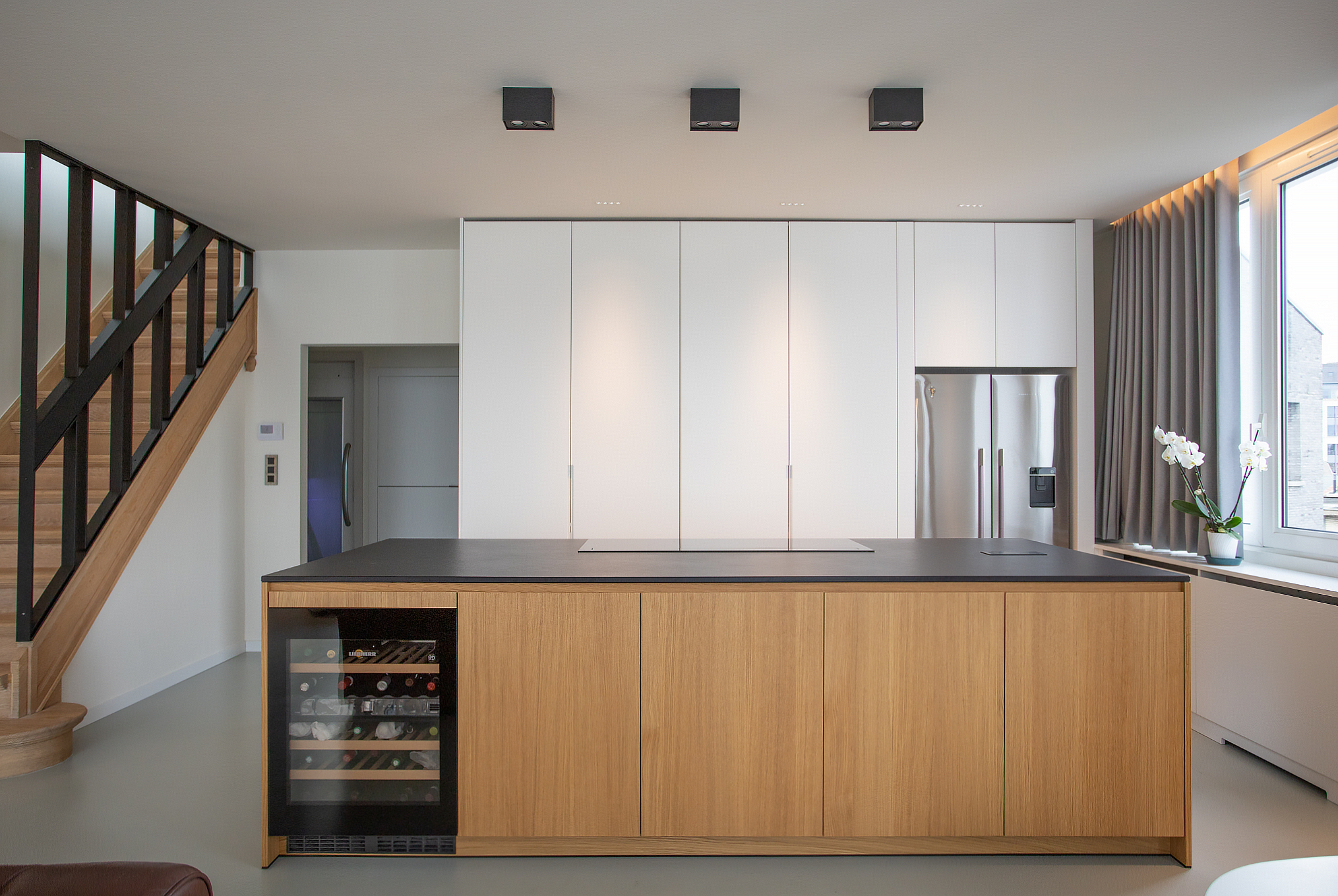 Bros Antwerpen maatwerk keuken inbouwkeuken eiland dekton sirius trap staal leuning kookplaat gietvloer wijnkast eiland eik gordijnen french fridge fisher&paykel wit